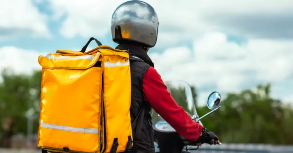 delivery person on motorcycle with yellow bag